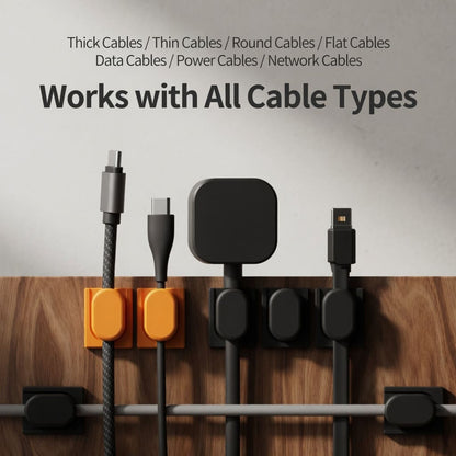 Orange magnetic cable organizer holding a USB-C cable on a dark desk surface